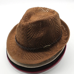 Close-up of knitted fedora texture with woven band and metallic oval plate detail