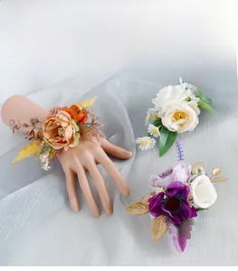 Detail of handmade wedding wrist corsage featuring artificial orange roses and gold leaves