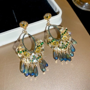 Close-up of vintage tassel earrings with green crystals and gold filigree metal