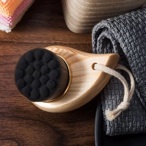 Detail of wooden facial cleansing brush with dense black fibers and woven lanyard