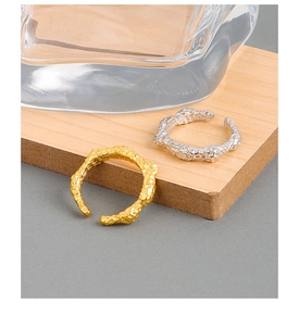 Macro di anelli in oro e argento con trama lavica irregolare e design a fascia aperta