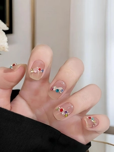 Detail of nude pink press-on nails with colorful rhinestones and white pearls