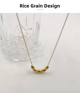 Detail view of gold titanium steel necklace featuring five rice-shaped beads on a fine chain
