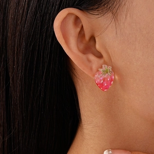 Nahaufnahme süßer rosa Erdbeer-Ohrstecker aus Harz am Ohr eines Models getragen
