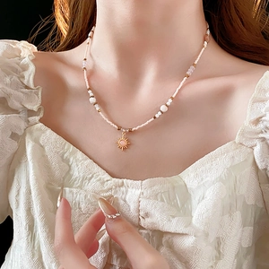 Detail of 18K gold sunflower necklace with pink crystal and beaded chain on model