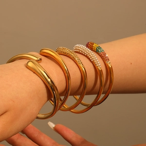 Five-piece golden stainless steel bracelet set featuring pearls, crystals, and smooth finish