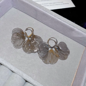 Détail de boucles d'oreilles pétales évidés argentés sur écrin en velours gris