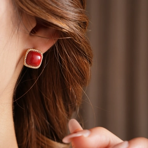 Macro view of gold-plated square red zircon earrings with clear diamond halo on model