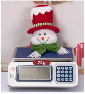 Detail showing a Christmas snowman doll weighing 72g on a digital electronic scale