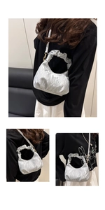 Detail of silver pleated cloud bag featuring scrunchie handle and metallic glossy finish