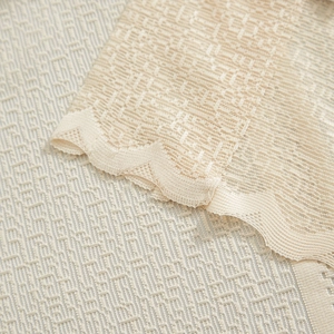 Detail of cream lace curtain with scallop edges and textured jacquard embroidery