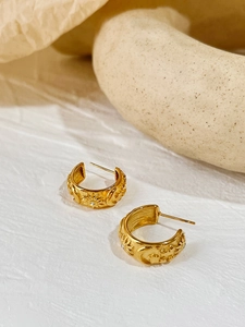 Detail of vintage gold C-shape earrings featuring celestial sun moon and star motifs