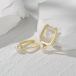 Macro detail of S925 sterling silver pearl earrings with zircon stones on white stone
