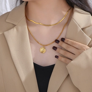 Close-up of double layer gold necklaces with crown pendant on a model's neck