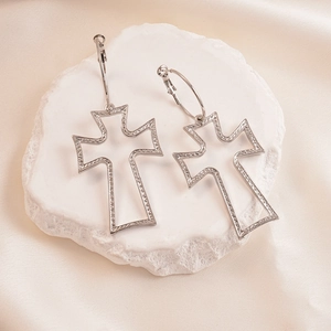 Silver hollow cross hoop earrings with textured finish on a white stone pedestal