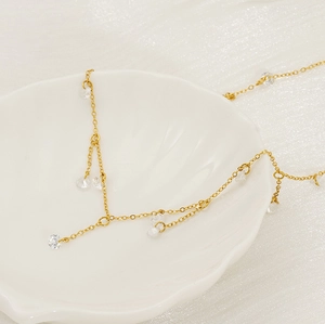Detailed close-up of golden tassel necklace with round zircon pendants on shell plate