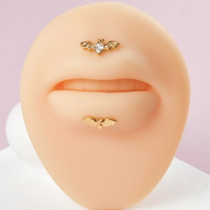 Studs de lèvre chauve-souris dorés avec zircone claire sur modèle de lèvre en silicone