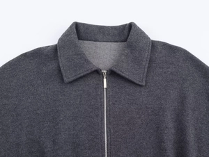 Close-up of a dark grey twill jacket featuring a metal zipper and lapel texture detail