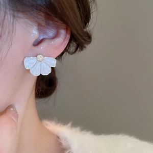 Gros plan de boucles d'oreilles fleurs blanches élégantes avec bords dorés sur modèle