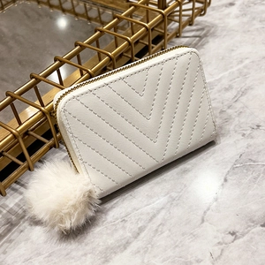 White V-quilted faux leather handbag with golden zipper and fluffy pompom charm
