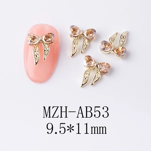 Vue détaillée de bijoux d'ongles nœuds dorés avec strass champagne, taille 9,5x11mm