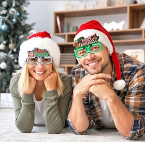 Men and women wearing Merry Christmas LED glasses with Santa and reindeer decor in a cozy setting