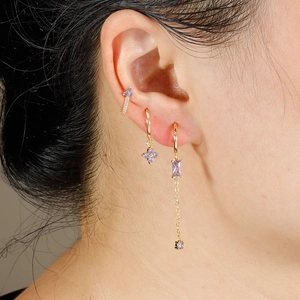 Close-up of golden earring set with purple zircons including flower cuff and long chains