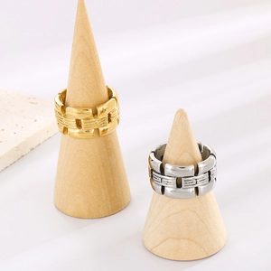 Nahaufnahme von geometrisch gerillten Edelstahlringen in Gold und Silber auf Holz