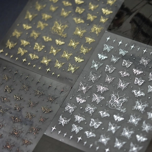 Close-up of butterfly and star nail stickers in gold and silver finish, style ID 2349