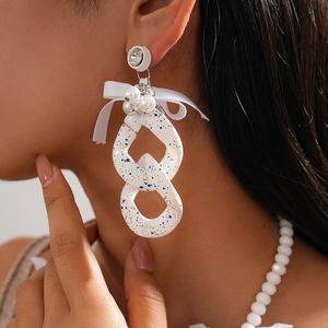 Close-up of model wearing chunky acrylic chain necklace with white bow and blue speckles
