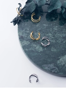 Detailed view of minimalist double-line cross ear cuffs in gold, silver, and black finishes