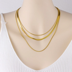 Three-layered golden snake chain necklace set shown on a mannequin over a white knit top