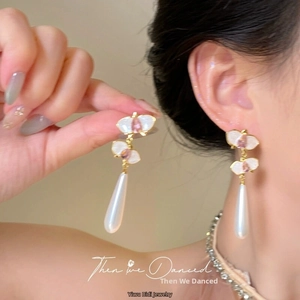 Detail of elegant gold butterfly earrings with purple enamel and teardrop pearl charms