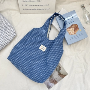 Gros plan sur un sac cabas à carreaux bleus avec étiquette vintage sur fond blanc