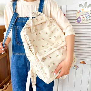 Detailed view of floral canvas backpack featuring pink flower patterns and front pocket