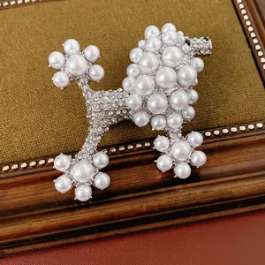 Vintage poodle pearl brooch with rhinestones on a green velvet base in a wooden frame