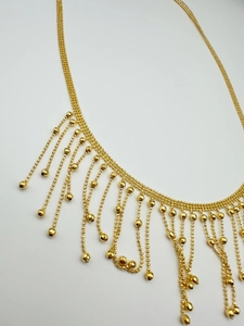 Detailed close-up of multilayer golden bead tassel necklace with a polished metallic finish