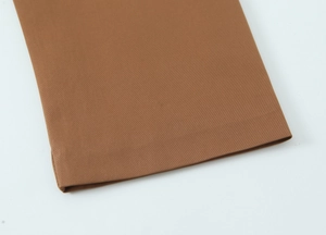 Close-up of brown trench coat sleeve cuff showing high-quality stitching and fabric texture