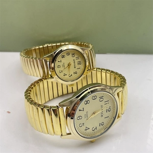 Close-up of gold quartz watches with elastic metal bands and large Arabic numerals