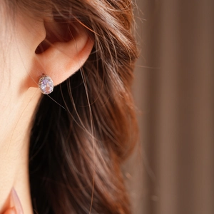 Close-up of elegant oval purple gemstone earrings with sparkling crystal accents