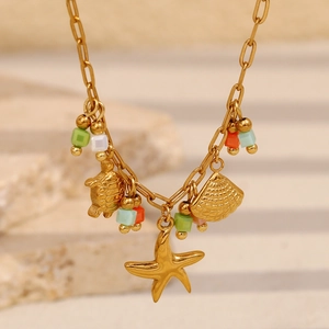 Gros plan d'un collier plaqué or 18 carats avec pendentifs tortue, pétoncle et étoile de mer