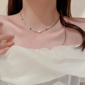 Gros plan d'un collier ras du cou en perles colorées avec pendentif fleur blanche