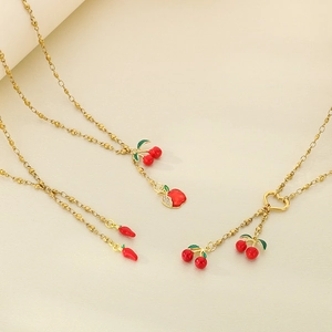 Detail view of red cherry, apple, and chili pendants on gold-plated stainless steel chains