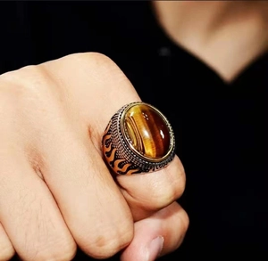 Retro men's tiger eye stone ring with vintage silver flame pattern etching on black background