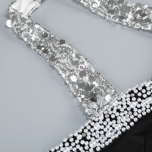 Macro view of silver sequins and white pearls on a dark off-shoulder dress