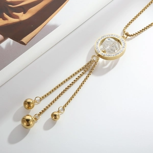 Macro shot of gold tassel pendant necklace with crystal ring and polished beads