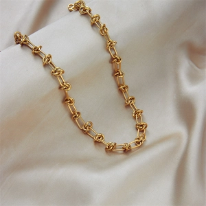 Gold-plated titanium steel necklace with thick woven chain on beige silk background