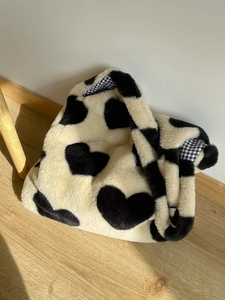 Close-up of heart pattern plush tote bag with blue checkered lining in sunlight