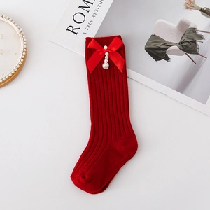Close-up of red knit socks featuring elegant satin bows and decorative pearls