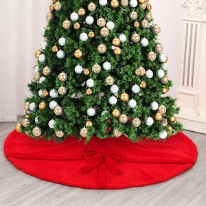 Red plush Christmas tree skirt with green bow decoration on grey wooden floor